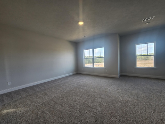 spare room with carpet, visible vents, and baseboards