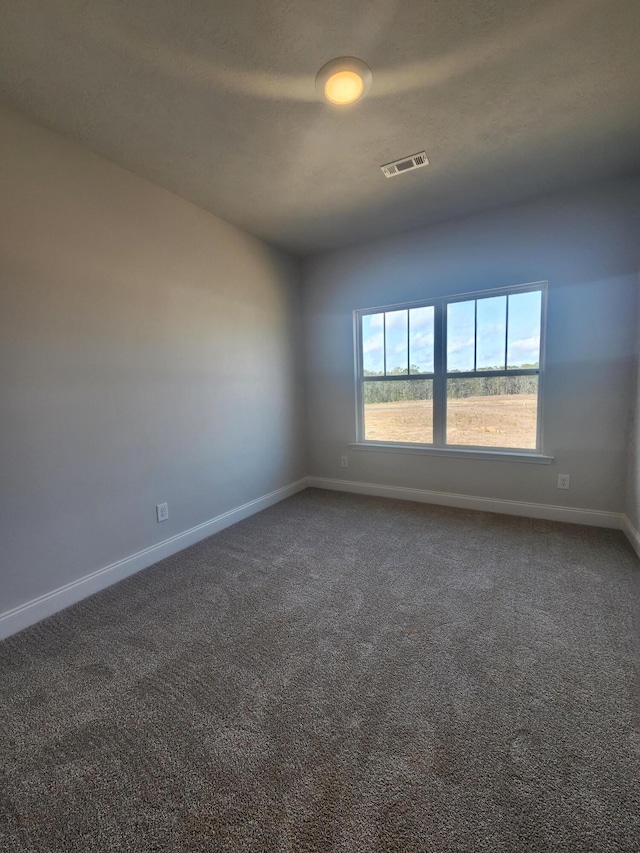 empty room with carpet floors, visible vents, and baseboards