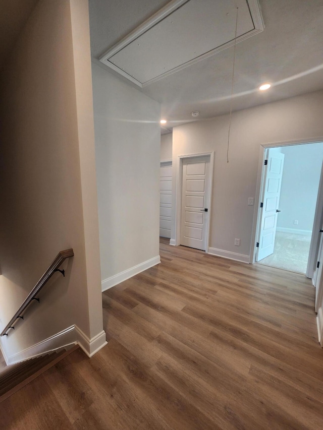 unfurnished room featuring attic access, baseboards, wood finished floors, and recessed lighting