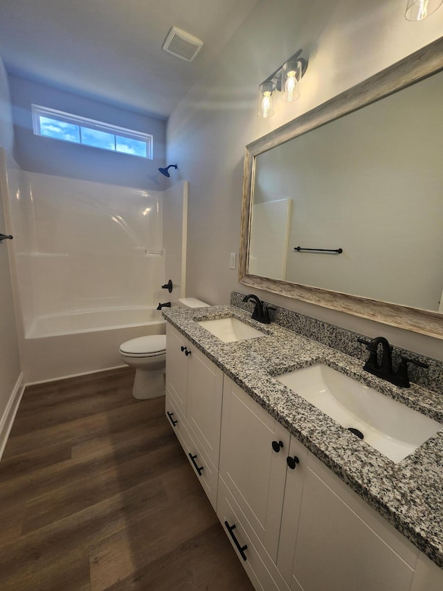 full bath featuring toilet, visible vents, a sink, and wood finished floors