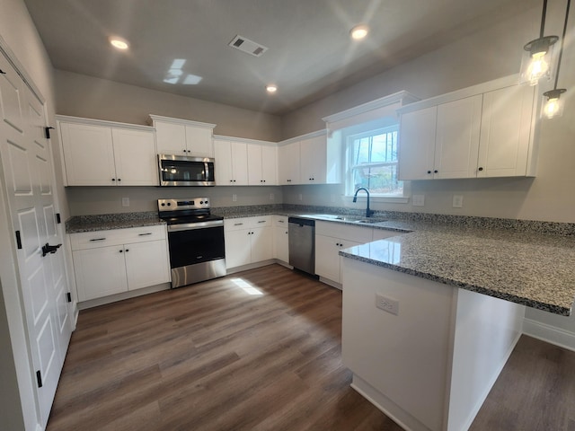 kitchen with appliances with stainless steel finishes, white cabinetry, a peninsula, and dark wood-type flooring