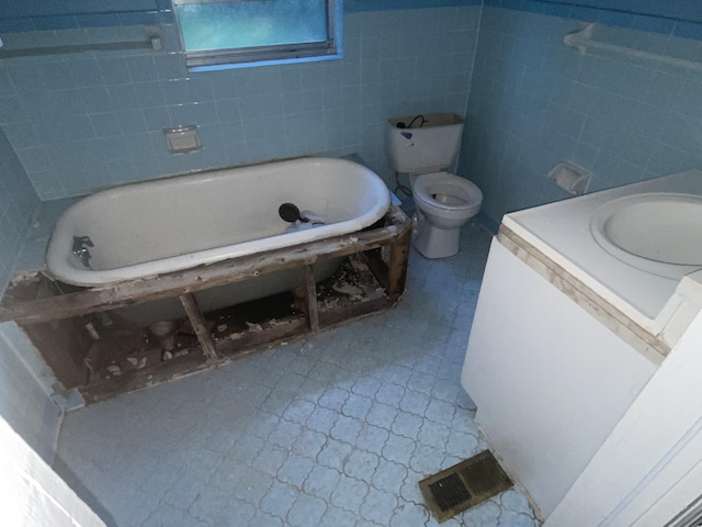 bathroom featuring vanity, a bath, tile walls, and toilet