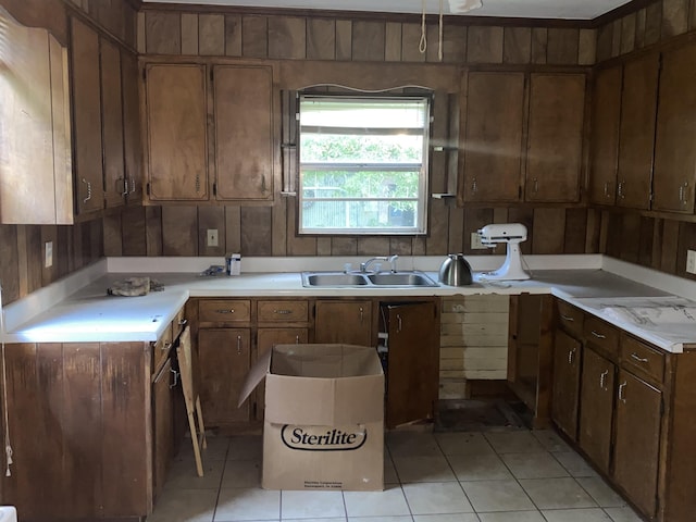 kitchen with light tile patterned floors, wood walls, and sink