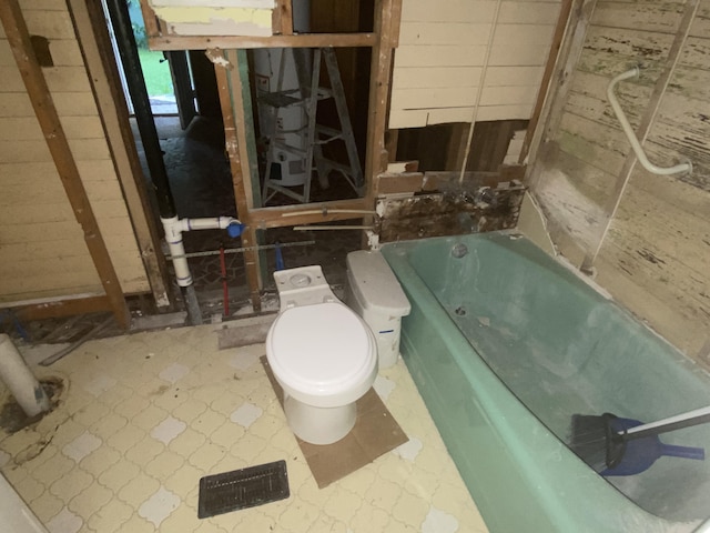 bathroom with toilet and a tub to relax in