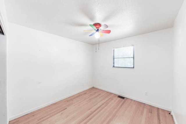 spare room featuring a textured ceiling, light wood-type flooring, and ceiling fan