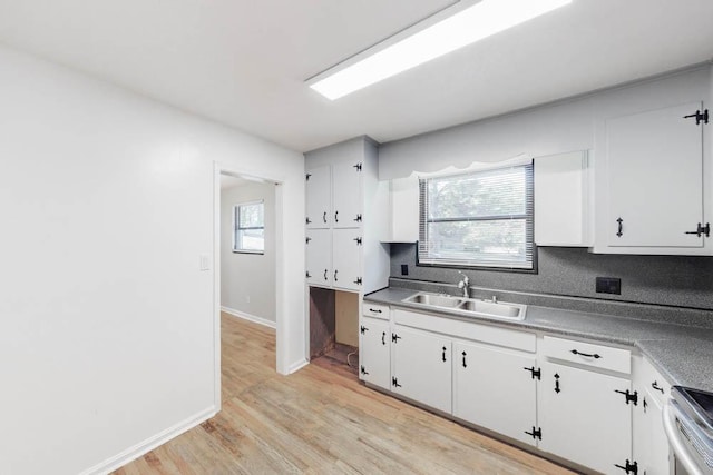 kitchen featuring white cabinets, light hardwood / wood-style floors, stove, and sink