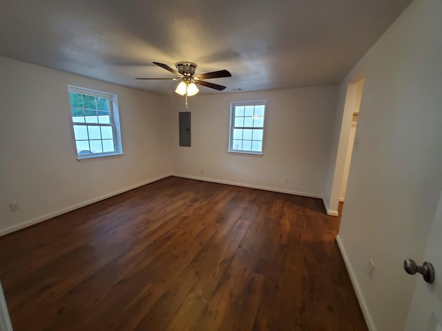 spare room featuring ceiling fan, electric panel, plenty of natural light, and dark hardwood / wood-style floors