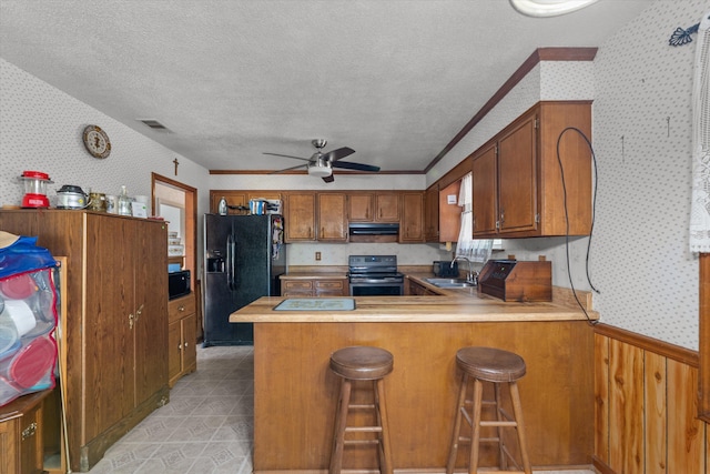 464 Rachel Dr, Evans, GA 30809 - kitchen with black appliances, wallpapered walls, brown cabinetry, a ceiling fan, and a peninsula