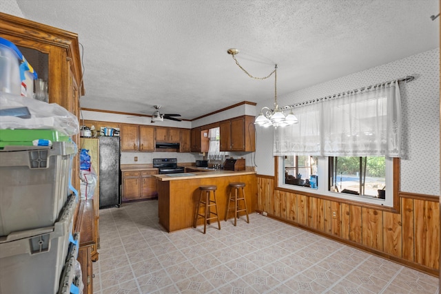 464 Rachel Dr, Evans, GA 30809 - kitchen featuring black appliances, brown cabinets, wainscoting, a textured ceiling, and under cabinet range hood