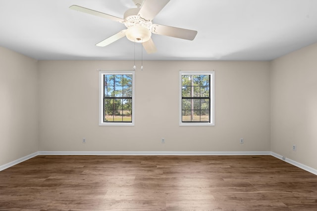 spare room with a wealth of natural light, dark wood-type flooring, and ceiling fan