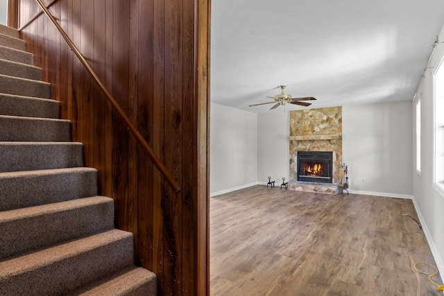 stairs featuring a fireplace, hardwood / wood-style floors, and ceiling fan