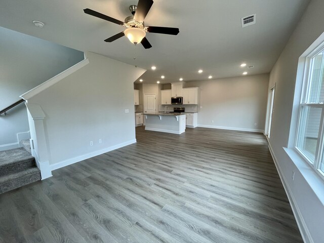 unfurnished living room featuring light hardwood / wood-style flooring, ceiling fan, and sink