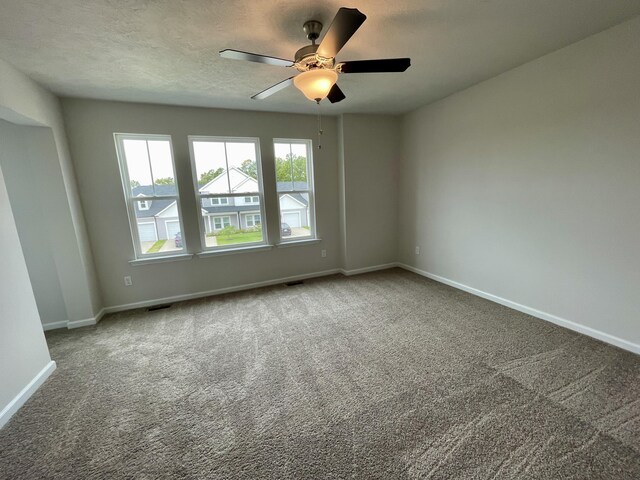 carpeted empty room with ceiling fan and a textured ceiling