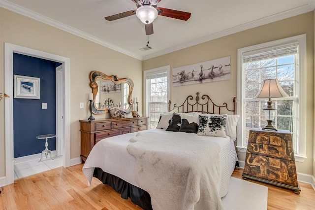 bedroom with multiple windows, light hardwood / wood-style floors, ceiling fan, and ornamental molding