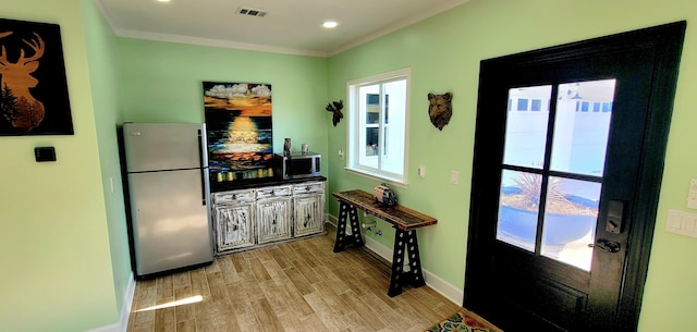 kitchen featuring crown molding, stainless steel appliances, and light wood-type flooring