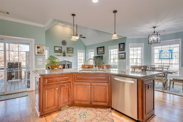 kitchen with stainless steel dishwasher, sink, a kitchen island with sink, and hanging light fixtures