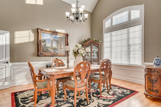 dining space with light wood-type flooring, lofted ceiling, and a chandelier