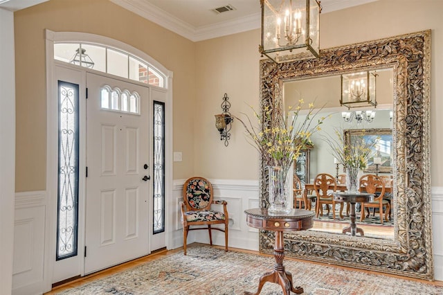 foyer with a chandelier, hardwood / wood-style floors, crown molding, and a healthy amount of sunlight