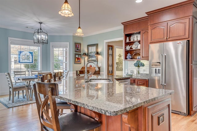 kitchen featuring a large island, sink, high end refrigerator, a chandelier, and decorative light fixtures