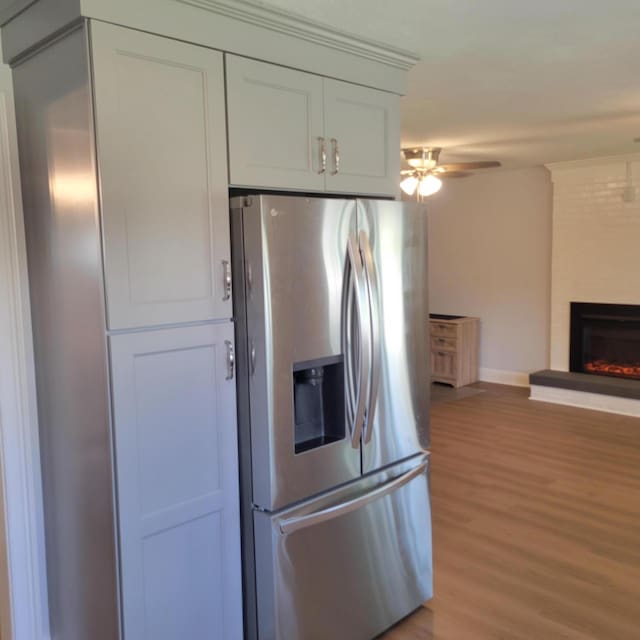 3597 Parliament Pl, Martinez, GA 30907 - kitchen featuring stainless steel fridge with ice dispenser, light wood-style flooring, ceiling fan, and a large fireplace