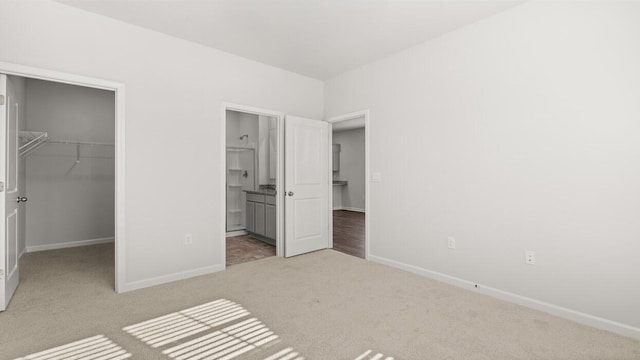 unfurnished bedroom featuring baseboards, a closet, a spacious closet, and carpet