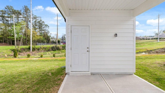 view of exterior entry featuring a lawn