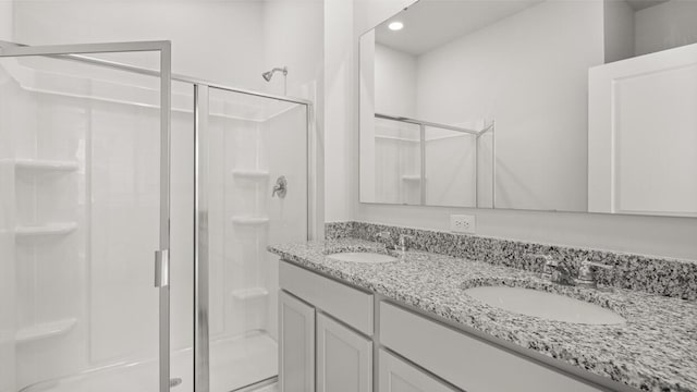 bathroom with double vanity, a sink, and a shower stall