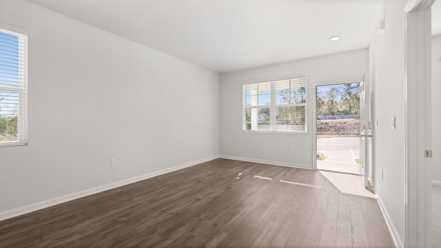 unfurnished room with dark wood-type flooring, baseboards, and a healthy amount of sunlight