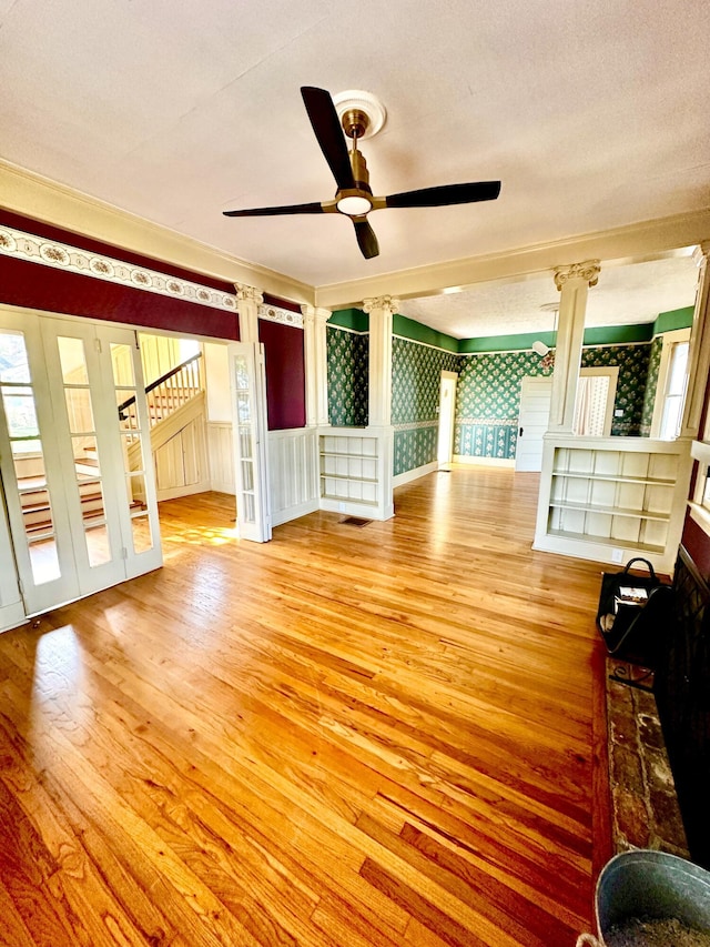 unfurnished living room featuring decorative columns, ceiling fan, light hardwood / wood-style floors, and a textured ceiling