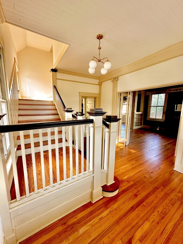 stairway with hardwood / wood-style floors and an inviting chandelier