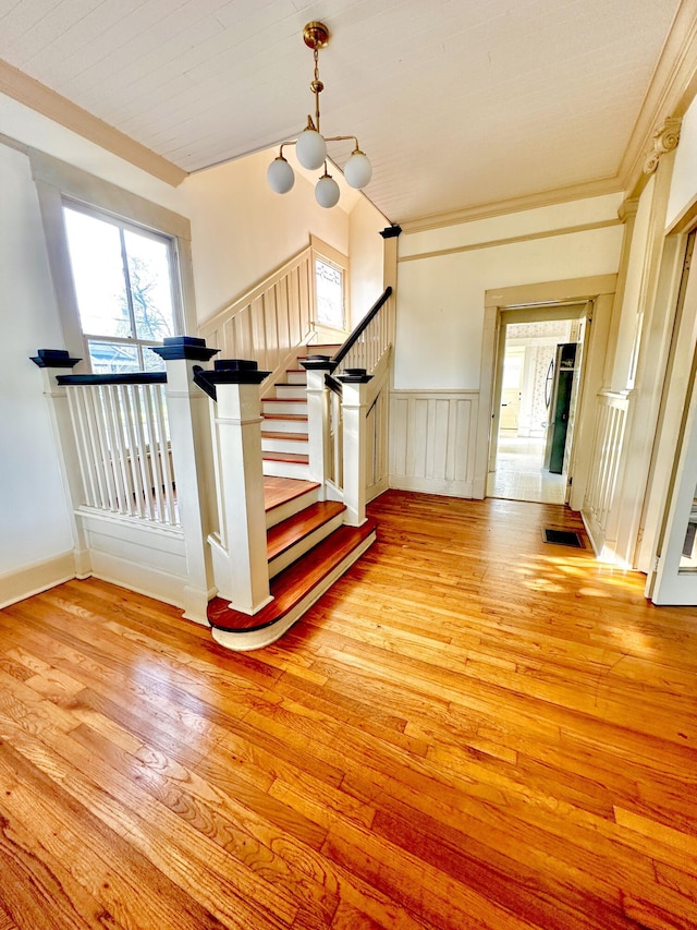 stairway with hardwood / wood-style flooring and ornamental molding