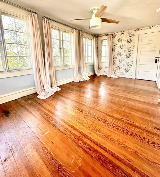 empty room with hardwood / wood-style floors, ceiling fan, and plenty of natural light