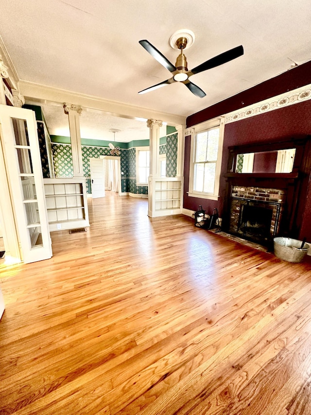 unfurnished living room with ceiling fan, light hardwood / wood-style flooring, a textured ceiling, and a brick fireplace