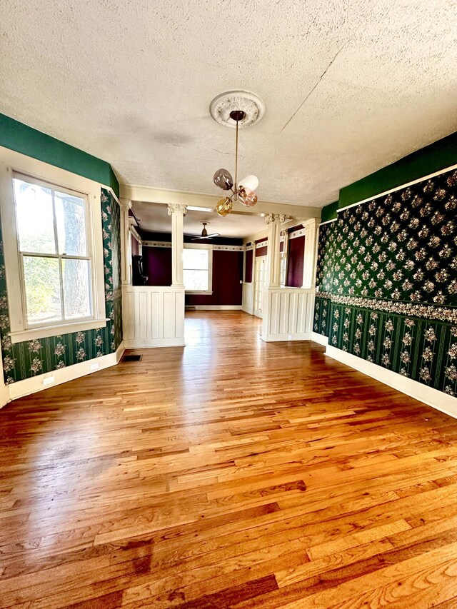 unfurnished room with wood-type flooring, a textured ceiling, and a chandelier