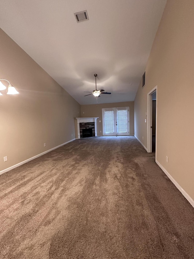 unfurnished living room with ceiling fan, a fireplace, vaulted ceiling, and dark colored carpet