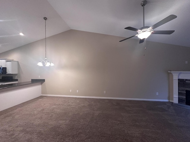 unfurnished living room with ceiling fan with notable chandelier, high vaulted ceiling, and carpet