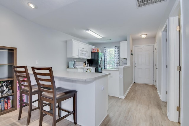 kitchen with white microwave, freestanding refrigerator, visible vents, light countertops, and range with electric cooktop