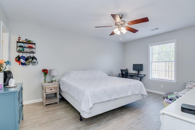 bedroom featuring light wood-style floors, baseboards, visible vents, and a ceiling fan