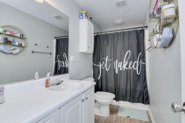 bathroom with vanity, visible vents, toilet, and wood finished floors