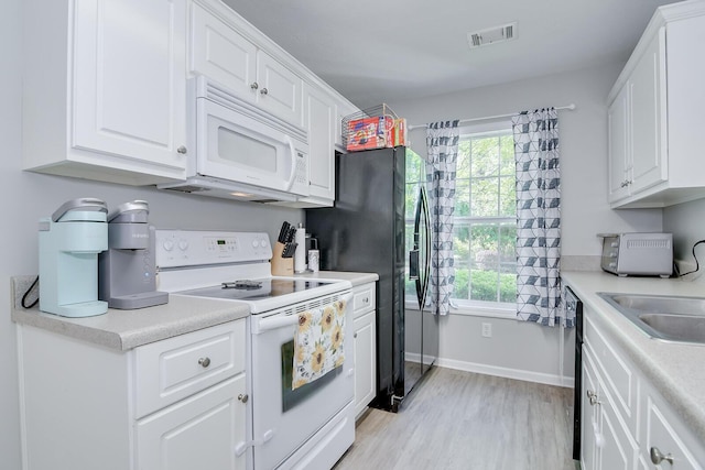 kitchen with light wood-type flooring, visible vents, black appliances, and plenty of natural light