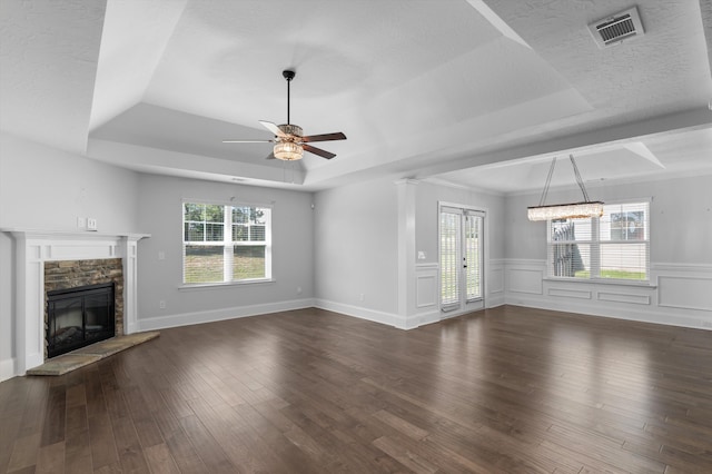 5174 Copse Dr, Augusta, GA 30909 - unfurnished living room featuring a tray ceiling, a stone fireplace, dark wood-style floors, a ceiling fan, and a wainscoted wall