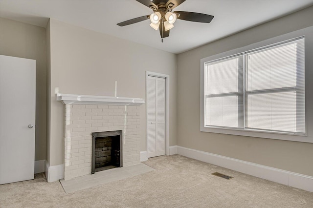 unfurnished living room with baseboards, a brick fireplace, a ceiling fan, and carpet