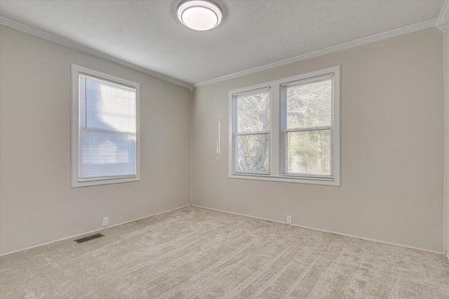 carpeted empty room featuring baseboards, ornamental molding, and visible vents