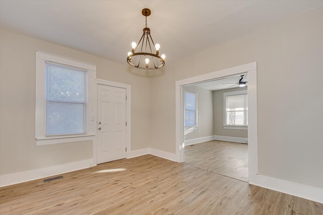 entryway featuring light wood-type flooring, an inviting chandelier, baseboards, and visible vents