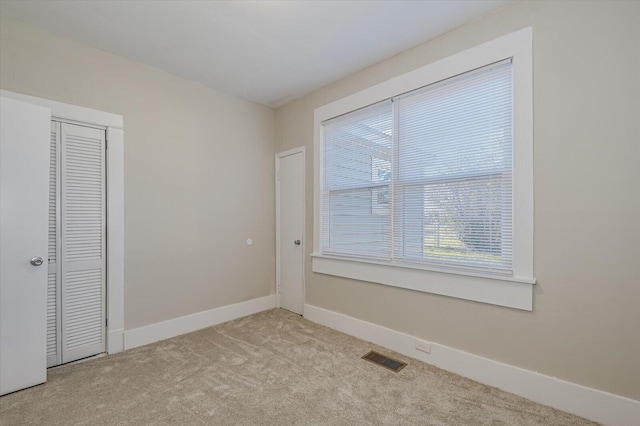 unfurnished room featuring carpet, visible vents, and baseboards