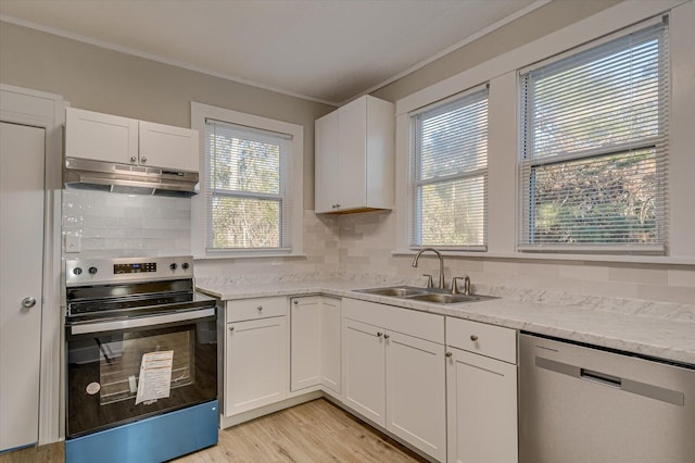 kitchen featuring tasteful backsplash, ornamental molding, under cabinet range hood, a sink, and stainless steel appliances