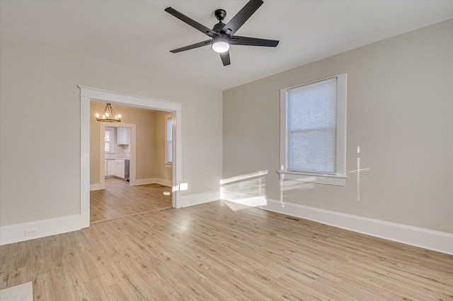empty room featuring visible vents, light wood-style flooring, baseboards, and ceiling fan with notable chandelier