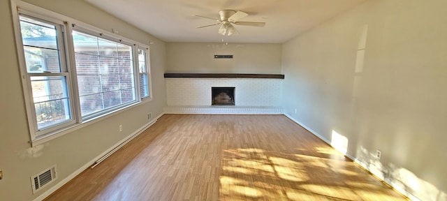 unfurnished living room featuring a brick fireplace, light hardwood / wood-style floors, and ceiling fan