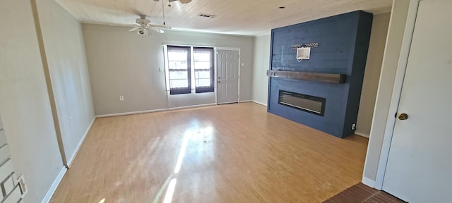 unfurnished living room with hardwood / wood-style flooring, a large fireplace, and ceiling fan