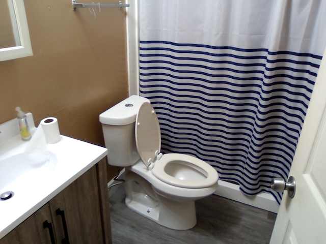 bathroom featuring wood-type flooring, toilet, vanity, and a shower with shower curtain